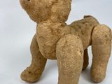 a brown teddy bear that is sitting on a white surface