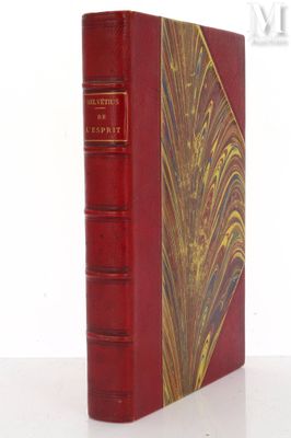 an old red book sitting on top of a table next to a white wall