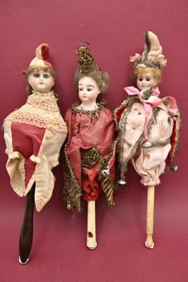 three antique dolls are lined up against a red background