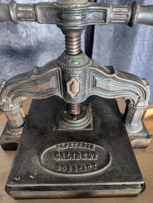 une vieille presse à imprimer en fonte posée sur une table en bois