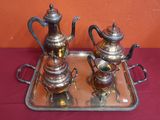two silver teapots sitting on a tray on a table