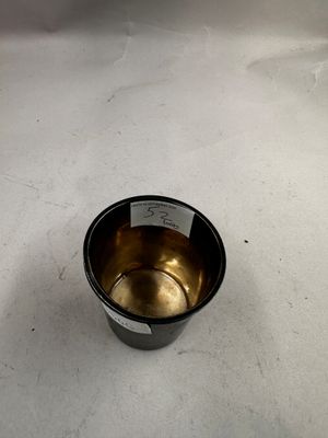 une tasse en métal posée sur une surface blanche