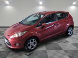 une Ford Fiesta rouge garée sur un sol à damier dans un garage