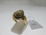 Gros plan sur une bague en or ornée d'une pierre verte