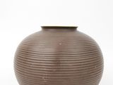 a brown vase that is sitting on a white surface