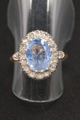gros plan d'une bague avec une pierre bleue entourée de diamants blancs