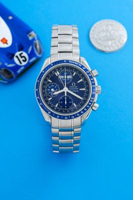 un gros plan d'une montre et d'une pièce de monnaie posées sur une surface bleue