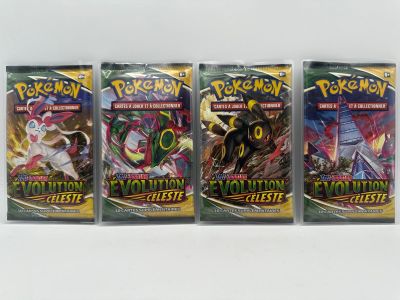 On voit trois paquets de cartes à collectionner Pokémon posés sur une surface blanche.