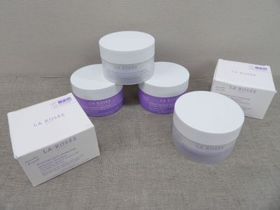 quatre flacons de produits de soin pour la peau, blancs et violets, posés sur une table