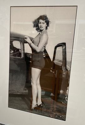 une photo en noir et blanc d'une femme adossée à une voiture