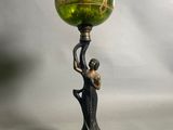 un vase vert posé sur un socle, tenu par une femme