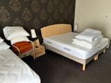 two beds in a room with a wallpapered wall