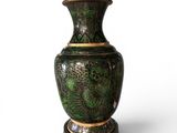 a green vase sitting on a stand on a white surface
