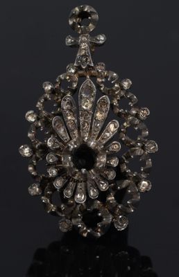 a close up of a diamond broochle on a black surface