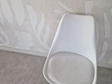 a white chair sitting in front of a wall with a plant on it
