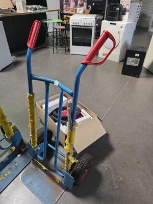 un petit chariot muni de deux poignées, posé à même le sol dans une pièce