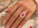 woman ' s hand with pink manicured nails and a red and white ring