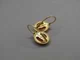 un gros plan sur une paire de boucles d'oreilles en or posées sur une surface grise