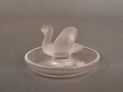a glass swan sitting on top of a glass ashtray