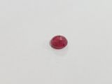 a single red ruby stone on a white surface