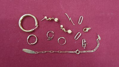 many different types of silver jewelry on a pink surface