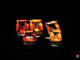 three pieces of yellow and orange glass sitting on top of a black surface