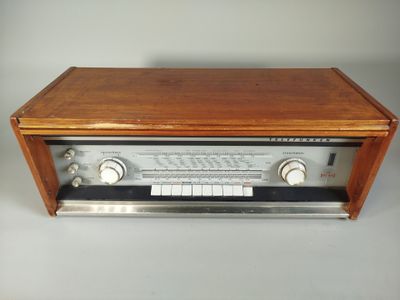 an old radio sitting on top of a wooden table next to a white wall
