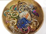 a wooden bowl filled with lots of jewelry on a table