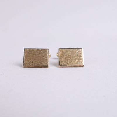 a pair of gold square stud earrings on a white background