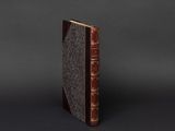 an old book sitting on top of a table next to a black background
