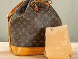 a louis vuitton bag and a towel on a wooden table