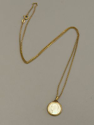 un gros plan d'un collier en or avec une pièce suspendue à une chaîne