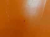 a toilet in a bathroom with an orange wall behind it