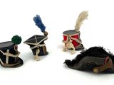 three miniature hats with feathers are sitting on a white surface