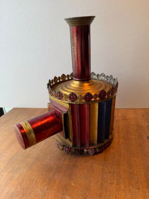 a red and gold vase sitting on a wooden table