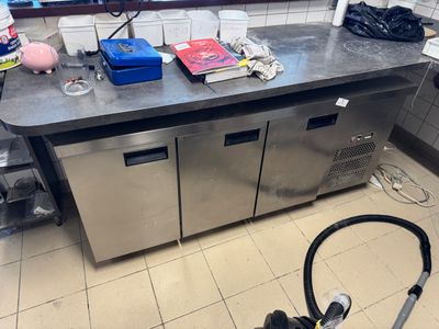 stainless steel counter top in a commercial kitchen with a vacuum on the floor