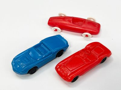 trois petites voitures assises l'une à côté de l'autre sur une surface blanche