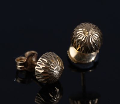 un gros plan sur une paire de boucles d'oreilles en or posées sur une surface noire