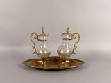 a gold plate with a silver and glass tea set on it
