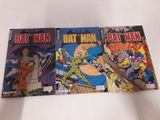 Trois bandes dessinées de Batman sont posées sur une surface blanche