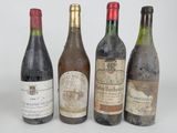 four bottles of wine are lined up in a row on a white surface