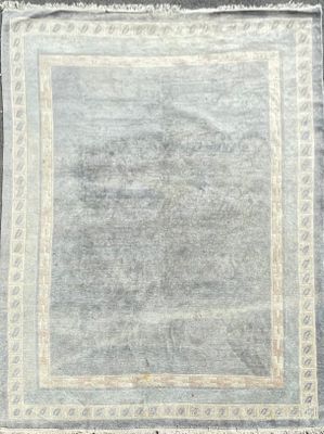 un tapis gris bordé de blanc posé sur un parquet
