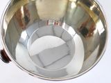 a metal bowl with a wooden handle on a white surface