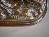 the bronze statue of a dog is sitting on a rock