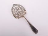 une cuillère en argent ancienne posée sur une surface blanche, avec une cuillère en argent au milieu