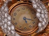 a gold clock with diamonds on it sitting on a table