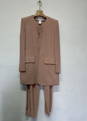 un costume beige suspendu à un cintre dans une pièce aux murs blancs
