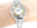 a silver and gold wrist watch with roman numerals on it