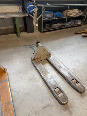 un chariot élévateur dans un garage où se trouve une étagère remplie d'outils