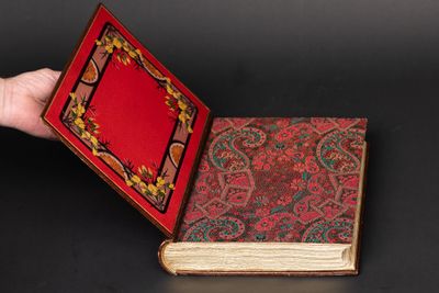 an open book with a red cover sitting on top of a black table